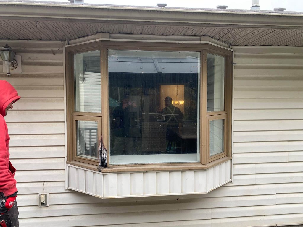 Before: old wood-trimmed bay window on white vinyl siding
